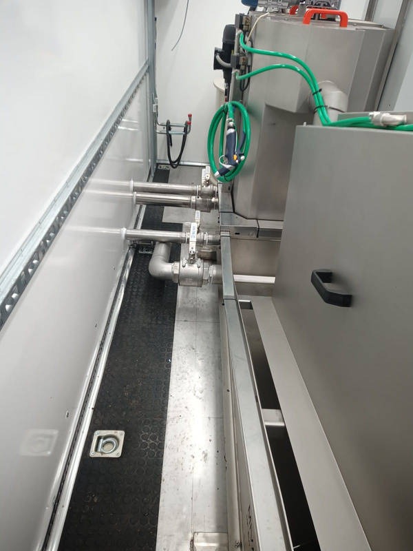 Wnętrze hali produkcyjnej z systemem rur i dysz rozpylających wodę, widoczne elementy stalowe i gumowa podłoga