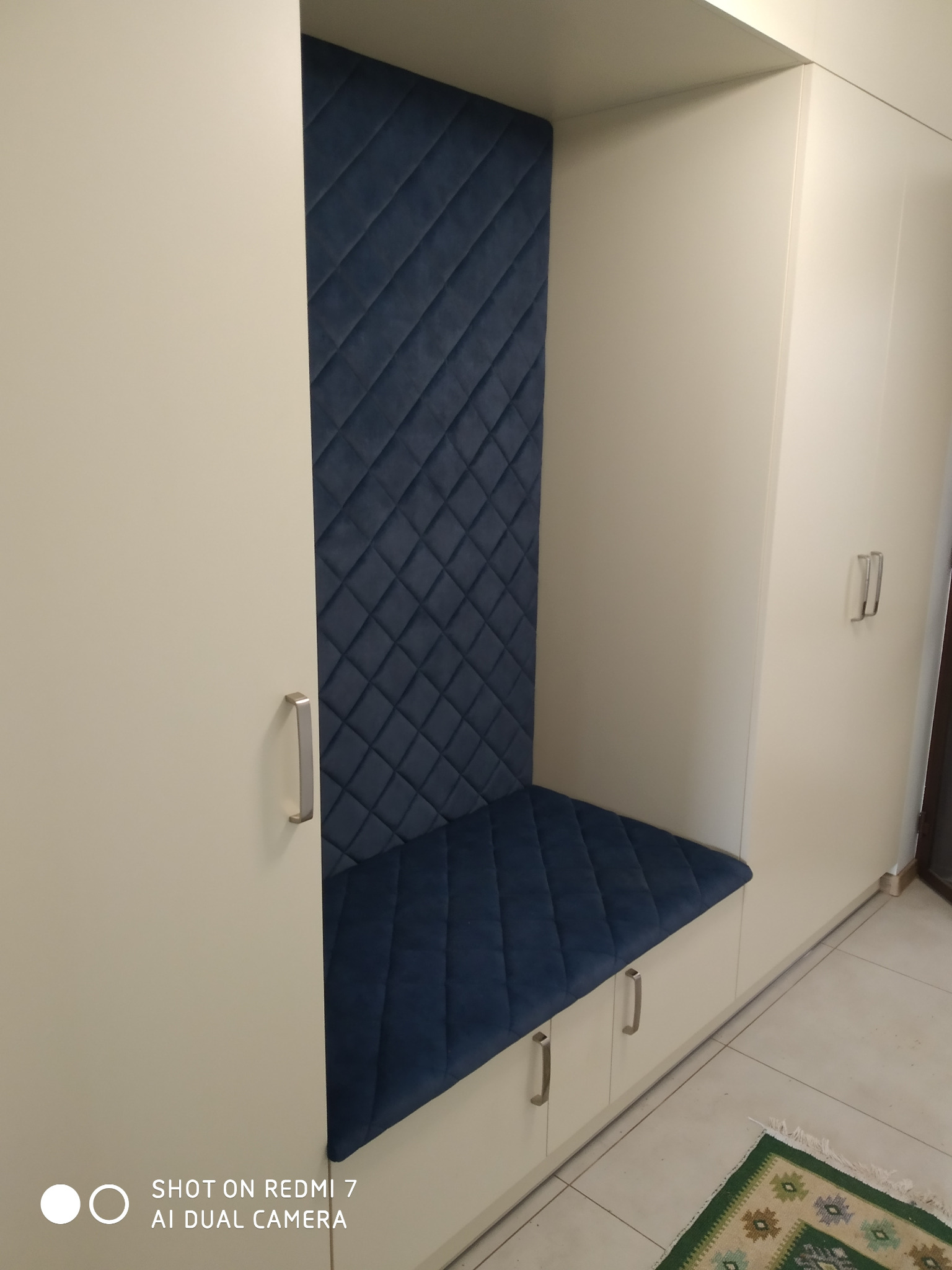 Białystok: Wnęka z siedziskiem i pikowanym, granatowym obiciem, wkomponowana w białą zabudowę szafy.