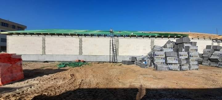 Budowa domu w Lipnie w trakcie wznoszenia ścian z betonu komórkowego i montażu konstrukcji dachu, widoczna drabina i palety z bloczkami.