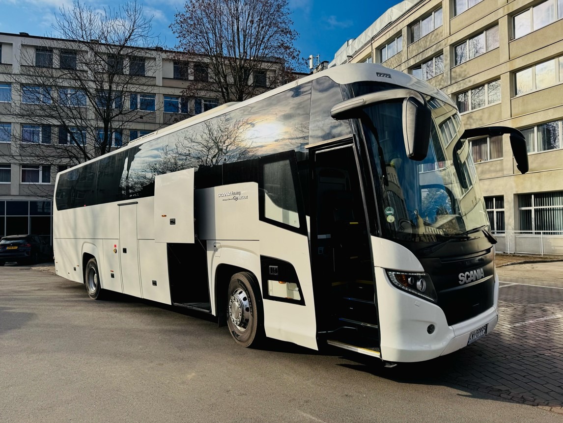 Nowoczesny autokar turystyczny Scania z otwartymi drzwiami na tle budynku