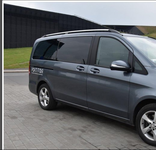 Szary van Mercedes z relingami dachowymi zaparkowany na brukowanym parkingu, z nazwą firmy 'PORTITOR' widoczną na boku.