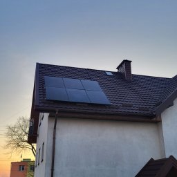 Zielony Program Ekologiczny sp. z o.o. - Dom jednorodzinny z brązowym dachem i panelami słonecznymi na połaci, widok z boku wczesnym rankiem.