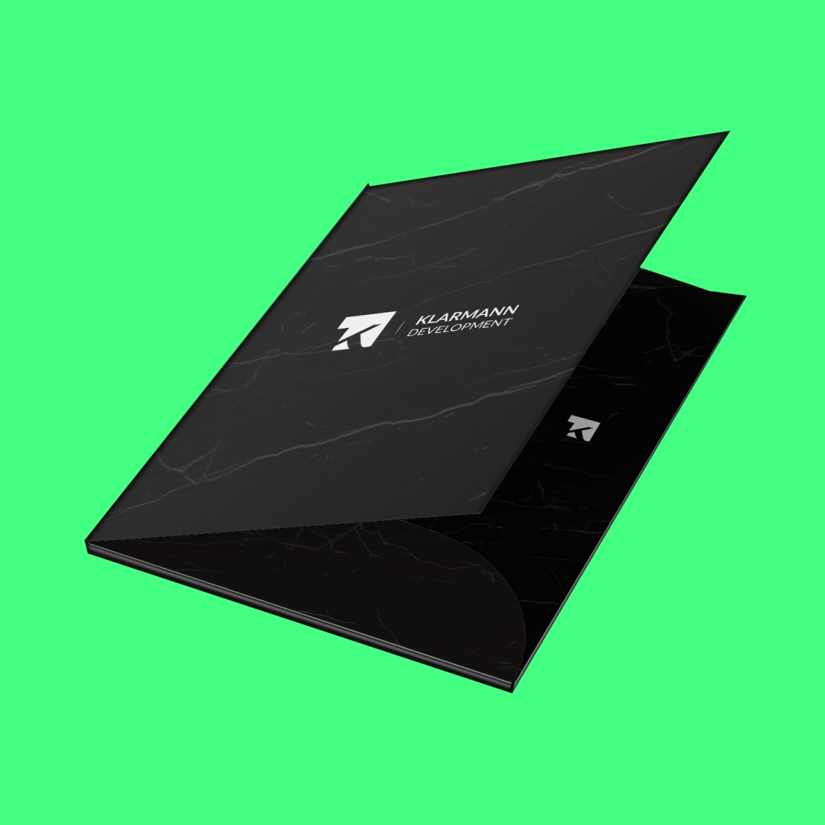 Czarna, otwarta teczka firmowa z marmurkowym wzorem i logo 'KLARMANN DEVELOPMENT' na tle jaskrawozielonym.