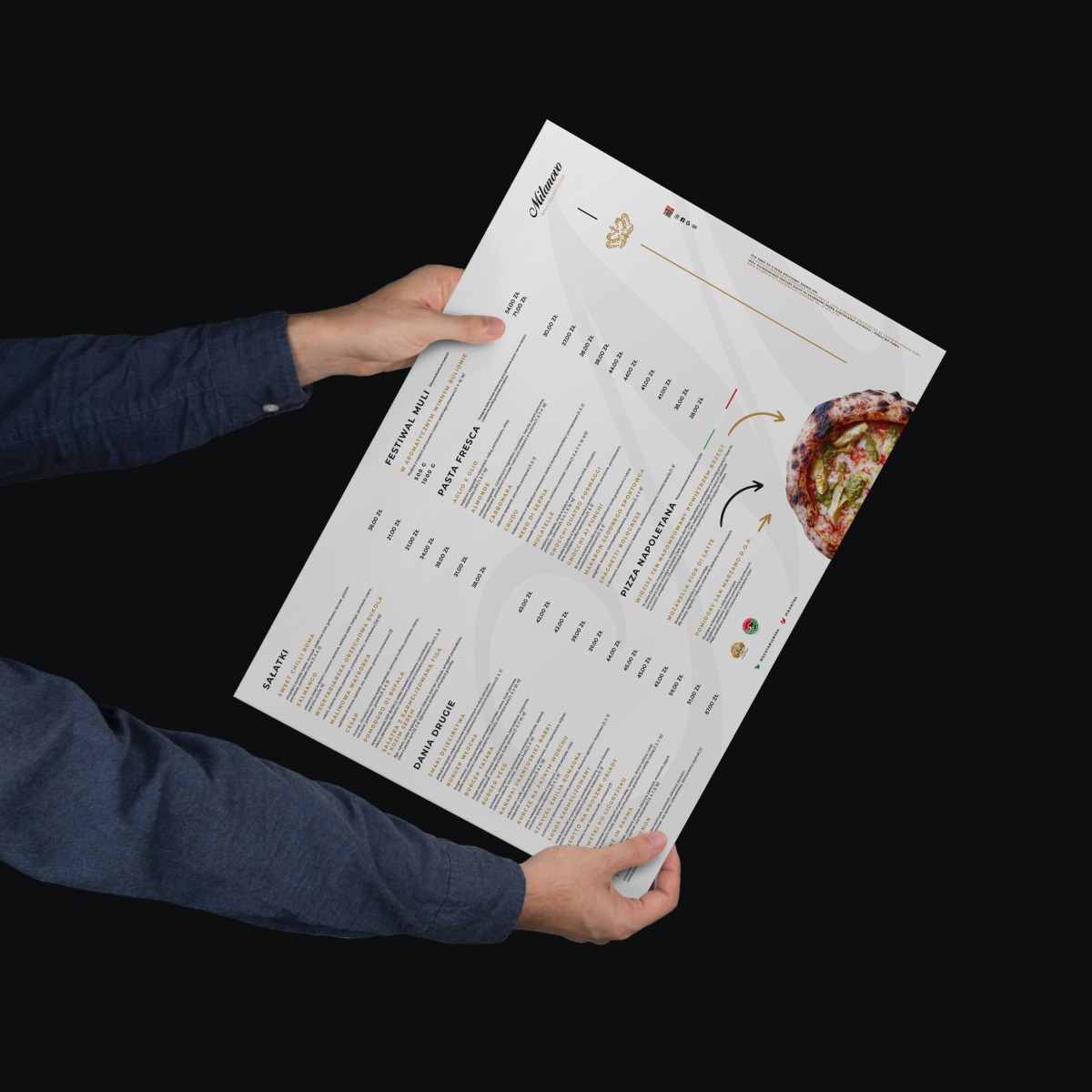 Męskie dłonie prezentują menu restauracji z wyraźnie widocznymi kategoriami dań, cenami i zdjęciem pizzy na ciemnym tle.