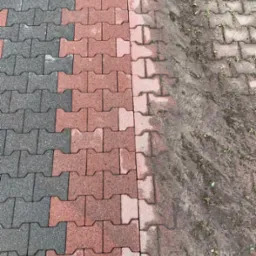 Częściowo wyczyszczona kostka brukowa w odcieniach szarości i czerwieni, z widoczną różnicą między czystą a zabrudzoną powierzchnią.