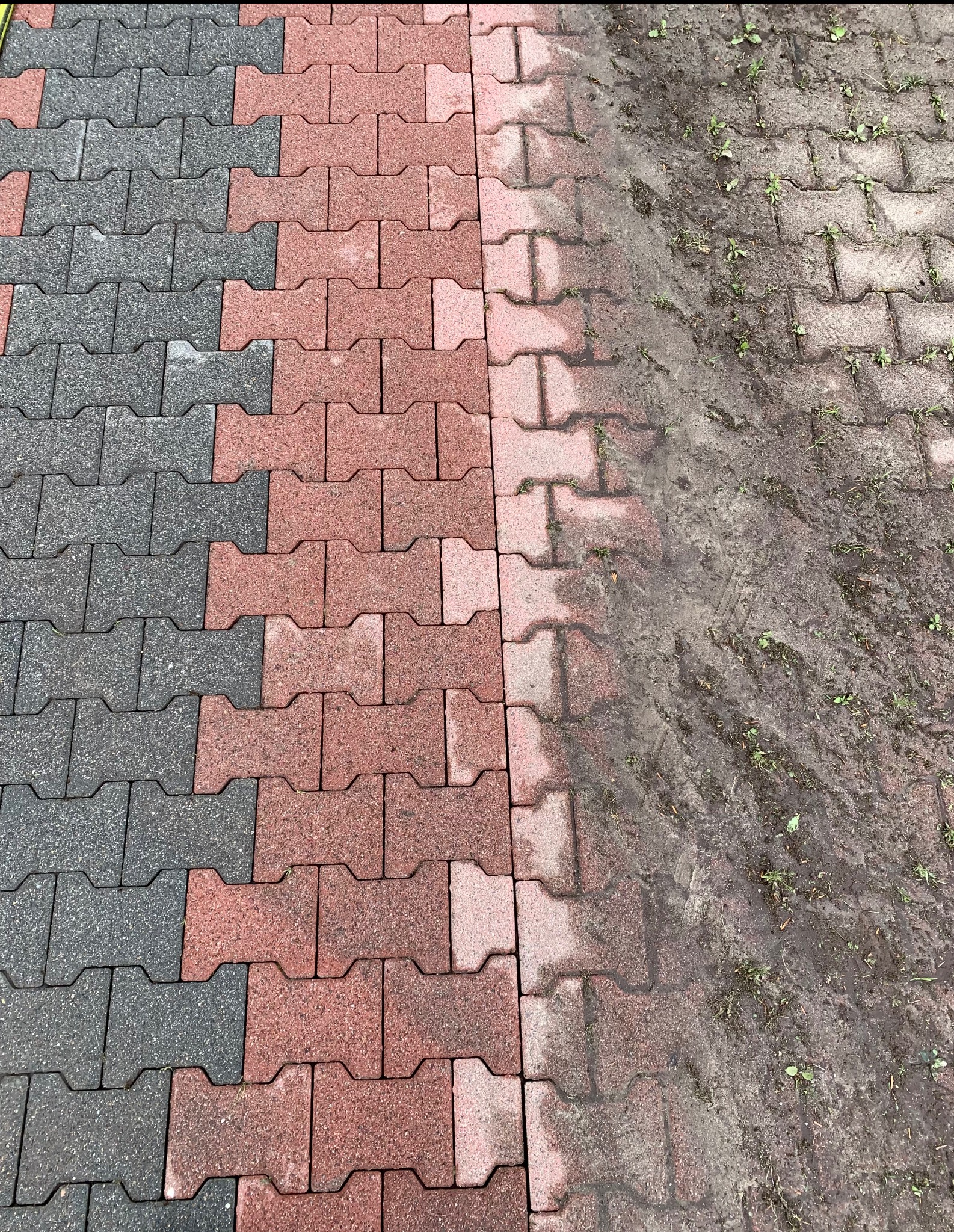 Częściowo wyczyszczona kostka brukowa w odcieniach szarości i czerwieni, z widoczną różnicą między czystą a zabrudzoną powierzchnią.