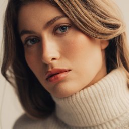 Joanna Tołwińska Fotografka - Portret młodej kobiety o jasnych włosach i niebieskich oczach, ubrana w kremowy golf, delikatny makijaż, naturalne światło.