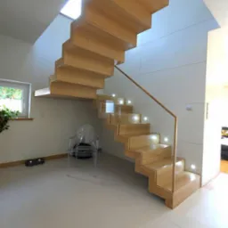 Nowoczesne, drewniane schody wiszące z podświetleniem LED, minimalistyczne wnętrze z białymi ścianami i przezroczystym krzesłem.