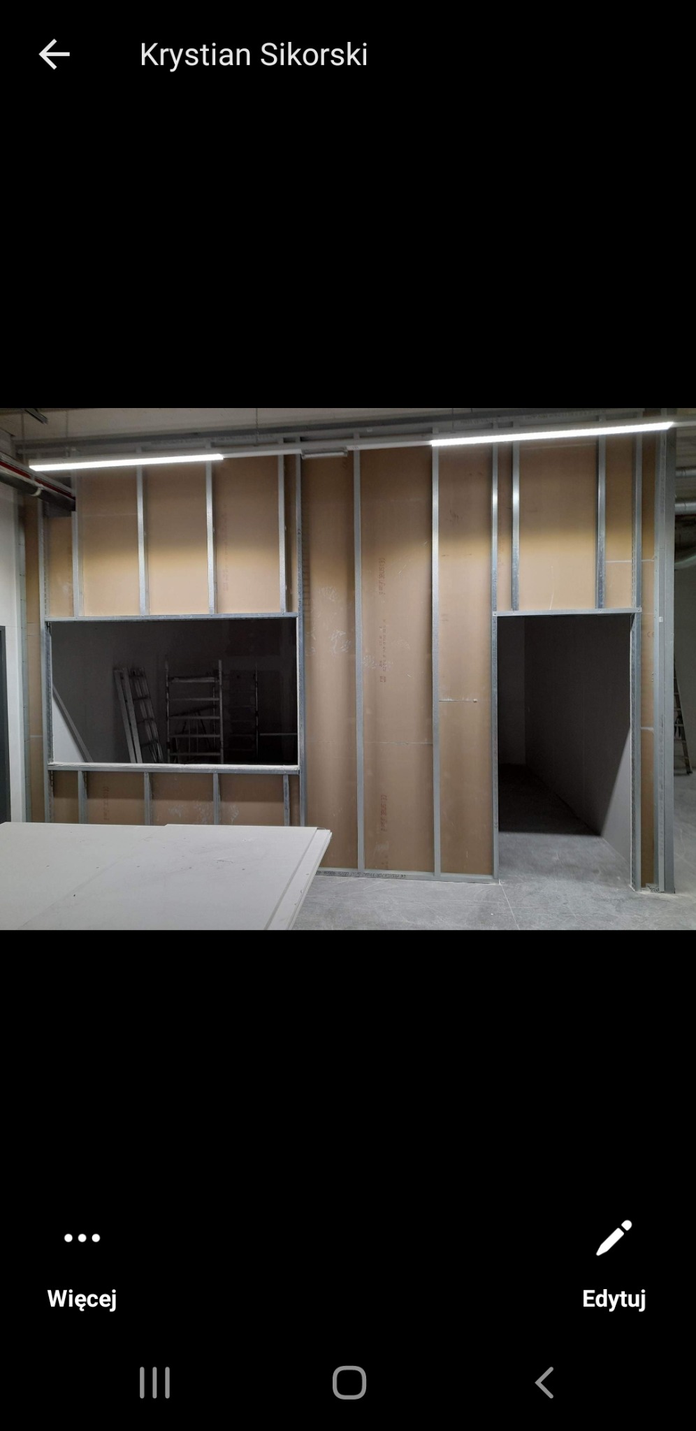 Wnętrze w trakcie budowy ścian działowych z płyt gipsowo-kartonowych na metalowym stelażu, widoczna drabina w otworze okiennym.