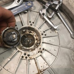 Paweł Roliński ROL-FIX - Wyjęty, zardzewiały element z pralki podczas naprawy. Widoczne narzędzia i zabrudzenia. Detal roboczy z bliska, ukazujący stan komponentu.