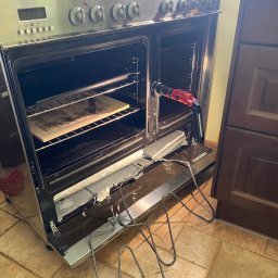 Paweł Roliński ROL-FIX - Uszkodzony piekarnik z wyciągniętą grzałką i narzędziem w środku, wnętrze oświetlone, ukazujące stan awarii przed naprawą.