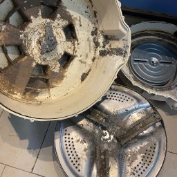 Paweł Roliński ROL-FIX - Brudne elementy pralki w trakcie demontażu: obudowa z osadem, bęben z widocznymi zabrudzeniami, metalowy element. Widoczne ślady użytkowania i zużycia.