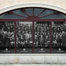 Czarno-biała fotografia dużej grupy umundurowanych strażaków i osób cywilnych umieszczona na okiennej folii reklamowej z adresem uStrazaka.pl.