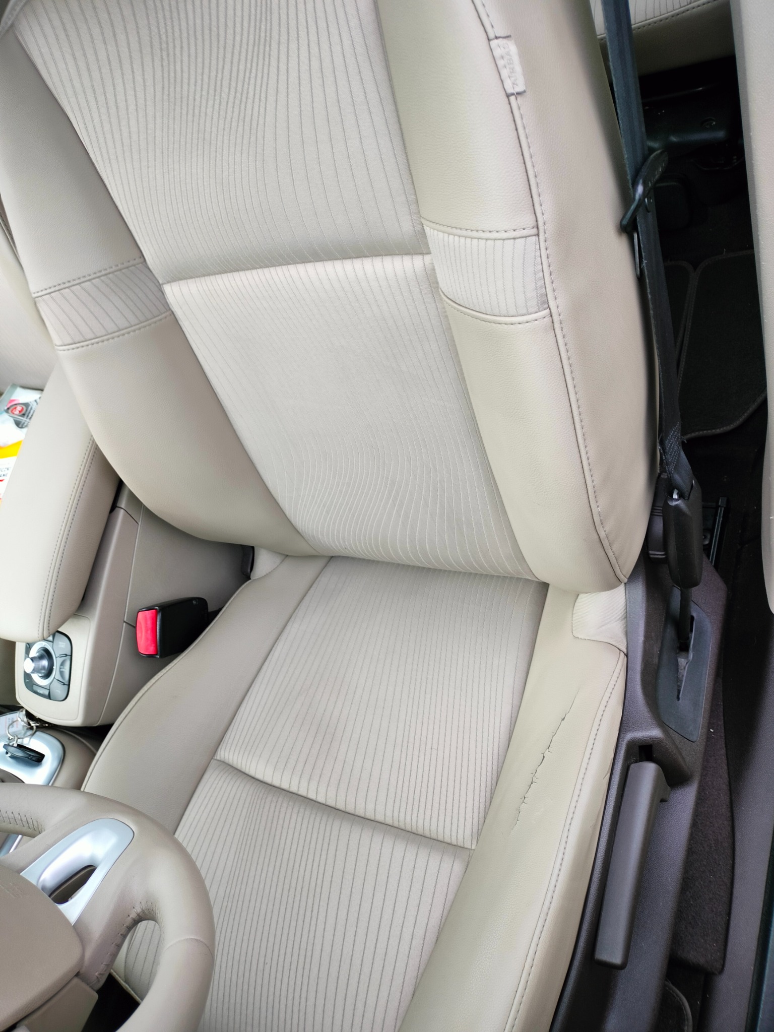 Beżowa skórzana tapicerka fotela samochodowego z widocznym pęknięciem na boku w Nowym Mieście nad Wartą.