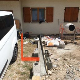 Blackwings - Wykonywanie fundamentów pod budynek w Rzeszowie: widoczny betonowy fundament, bloczki betonowe, betoniarka oraz samochód dostawczy firmy.