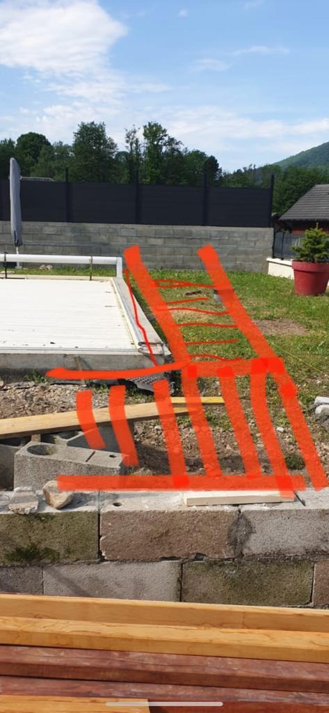 Budowa tarasu: Widok na częściowo ukończony taras z betonowych bloków i drewnianych belek, zarys drabiny na zdjęciu.