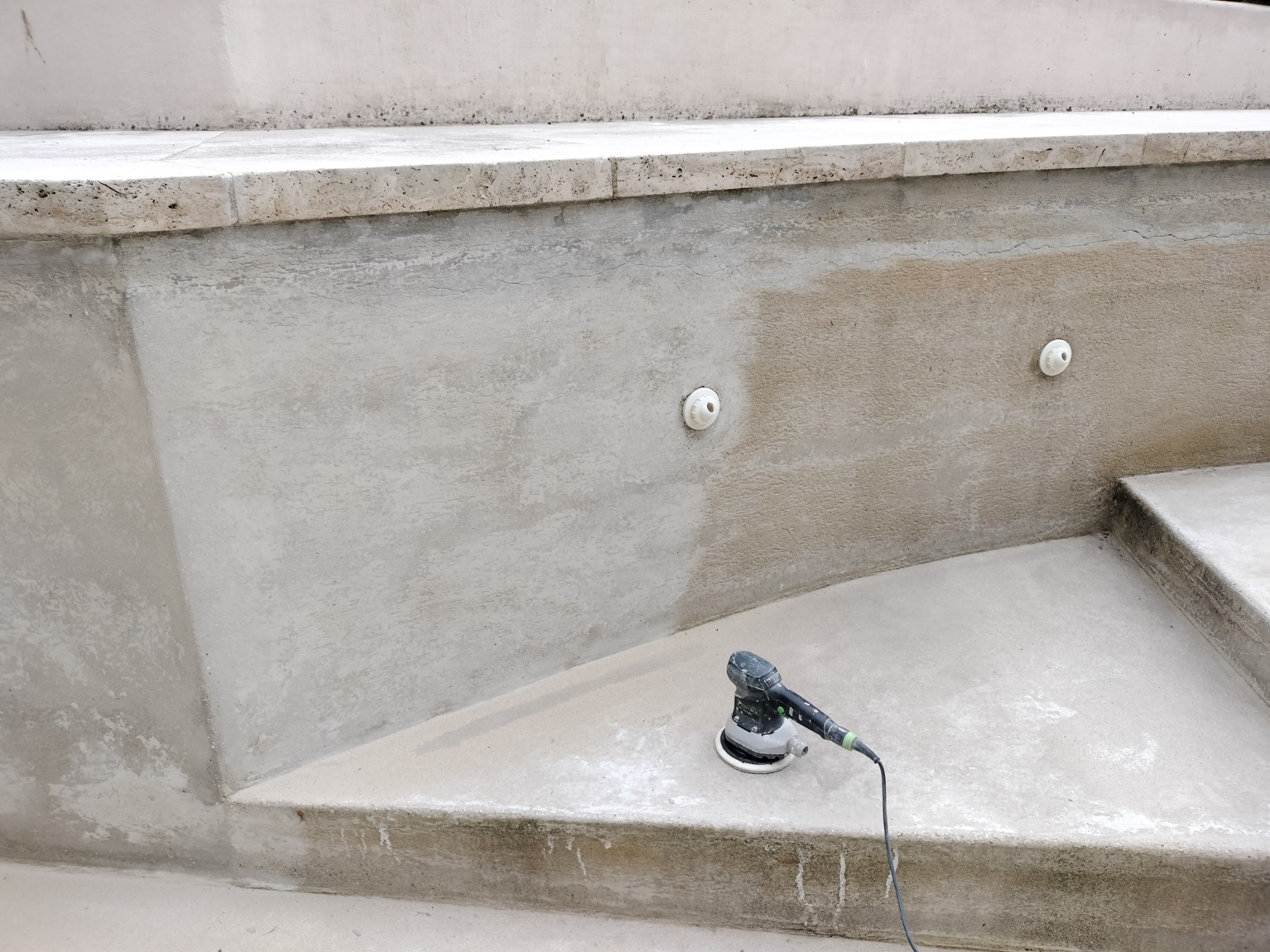 Szlifowanie ściany schodów z gładzi, widoczne różnice w fakturze po szlifowaniu, szlifierka oscylacyjna na stopniu.