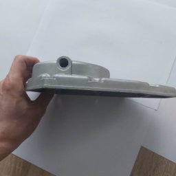 MARKING - Szara, aluminiowa obudowa z otworem, trzymana w dłoni na tle białego papieru