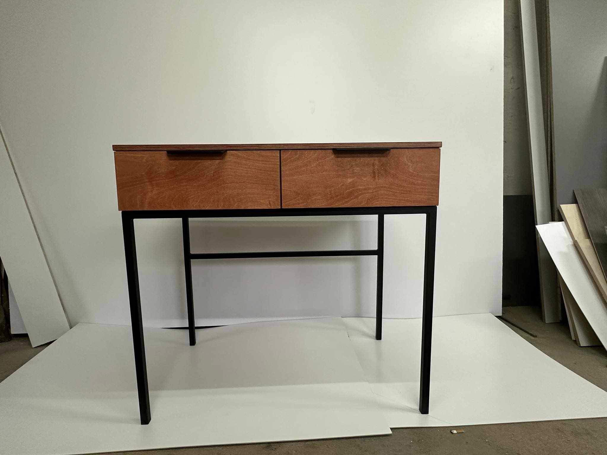 Nowoczesna konsola z dwoma drewnianymi szufladami i czarnymi metalowymi nogami, ustawiona na białym tle w warsztacie.