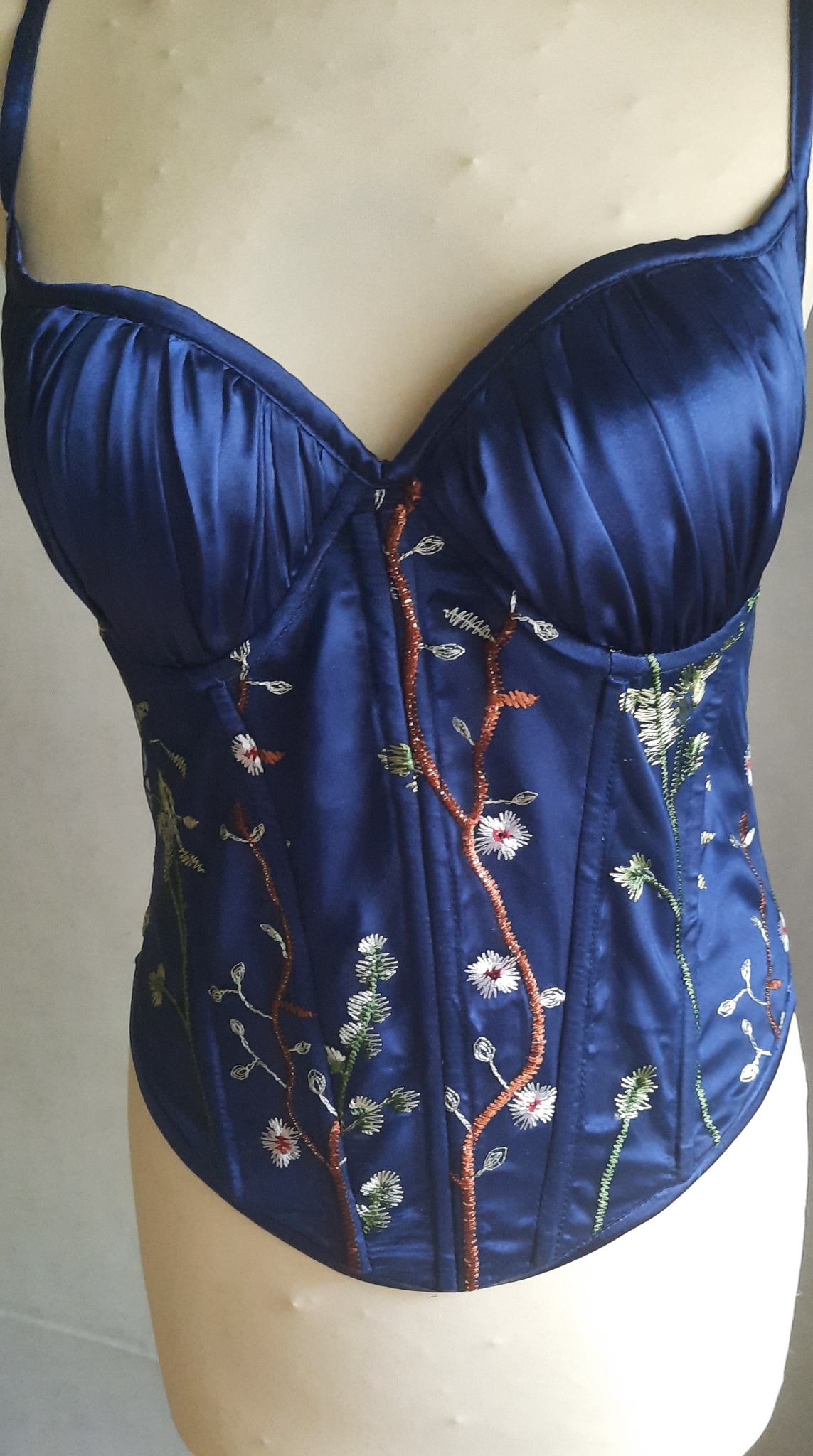 Niebieski satynowy gorset z haftowanymi motywami roślinnymi, eksponowany na manekinie.