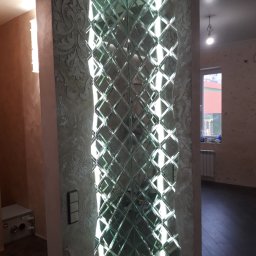 Dream_house_pl_ua - Dekoracyjny panel lustrzany z romboidalnych elementów na ścianie, obok kolumny z ozdobnym tynkiem strukturalnym i włącznikiem światła.