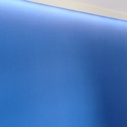 KOMPLEX MB - Niebieska ściana z delikatną teksturą w jodełkę, oświetlona od góry listwą LED, widoczny fragment białej ściany i drzwi.