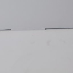 SaVo - Fragment świeżo pomalowanej, jednolitej ściany w jasnym odcieniu z widocznym łączeniem z sufitem zabezpieczonym taśmą malarską.