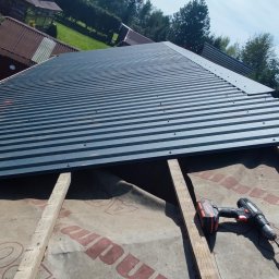 SaVo - Montaż blachy trapezowej na dachu, widoczne łaty, membrana dachowa i wkrętarka akumulatorowa.