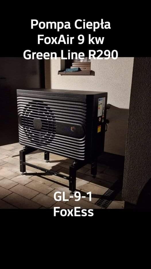 Czarna pompa ciepła FoxAir 9 kw Green Line R290, model GL-9-1 FoxEss, ustawiona na metalowym stelażu na tle ściany z półką.