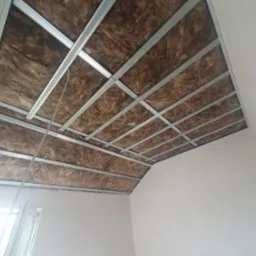 Poddasze z widoczną izolacją z wełny mineralnej umieszczoną między metalowymi profilami konstrukcji sufitu podwieszanego, przygotowane do montażu płyt karton-gips.