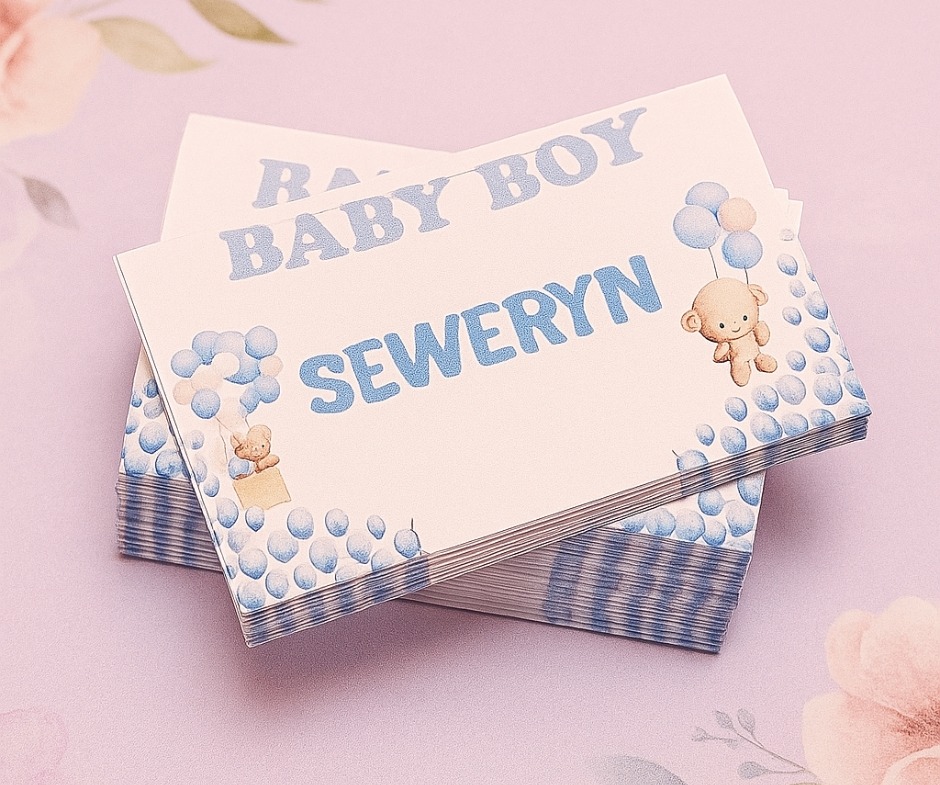 Stos winietek 'Baby Boy Seweryn' z motywem pluszowego misia i błękitnych balonów, ułożony na bladoróżowym tle. Delikatna grafika, czcionka w pastelowych odcieniach.