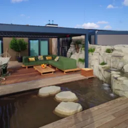 Nowoczesny taras na dachu z drewnianą podłogą, zieloną sofą narożną, sztucznym wodospadem i oczkiem wodnym z kamiennymi stopniami, pergola metalowa z przesuwnymi panelami.