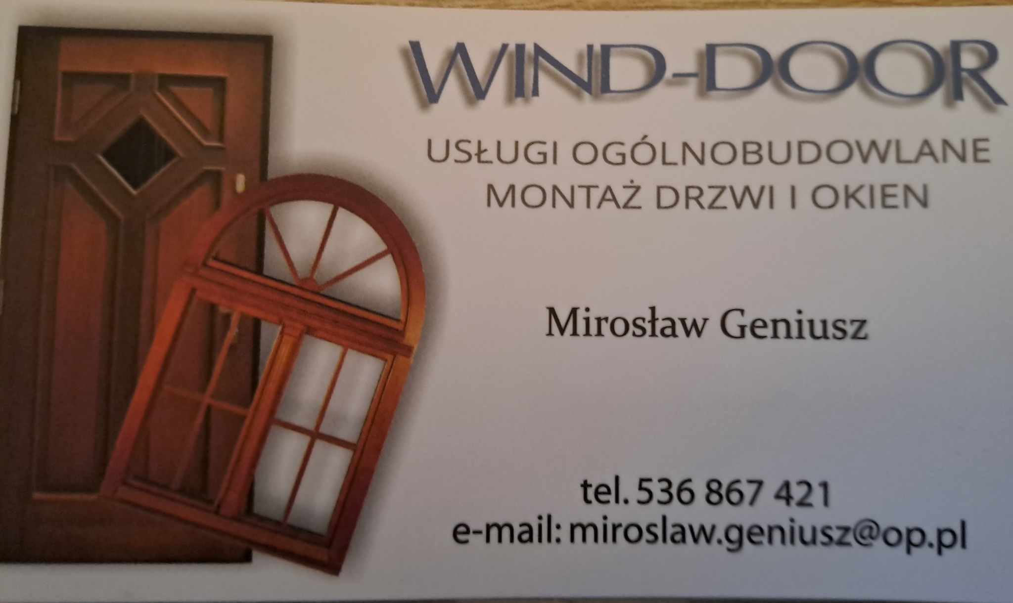 Wizytówka firmy Wind-Door z ilustracją brązowych drzwi i okna, oferującej usługi ogólnobudowlane oraz montaż drzwi i okien, z danymi kontaktowymi Mirosława Geniusza.