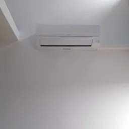 Biały klimatyzator marki Mitsubishi zamontowany na białej ścianie w pomieszczeniu z białym sufitem.