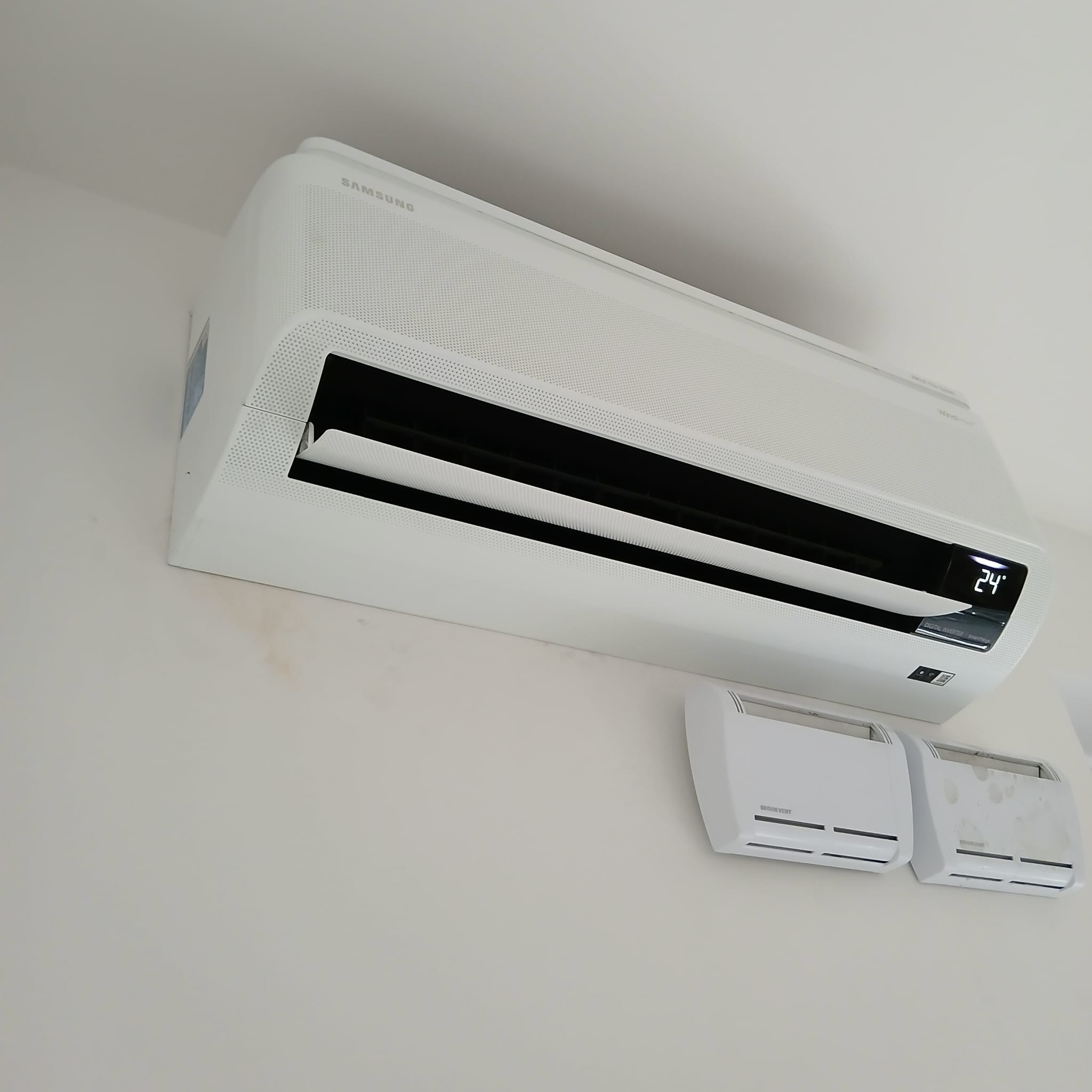Nowoczesny, biały klimatyzator Samsung zamontowany na ścianie, z widocznymi dwoma anemostatami, jeden z nich jest zabrudzony.