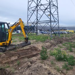 Kris-Bud - Żółta mini koparka JCB 8018 CTS podczas wykonywania wykopu liniowego w ziemi, z widoczną linią wysokiego napięcia w tle.