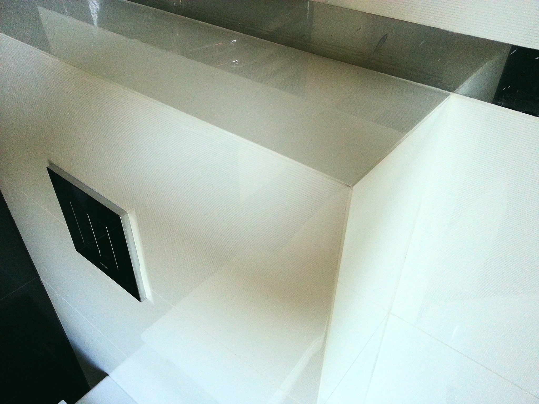 Nowoczesna łazienka z białymi, poziomymi płytkami i czarnym panelem sterowania spłuczką, ujęcie z góry.