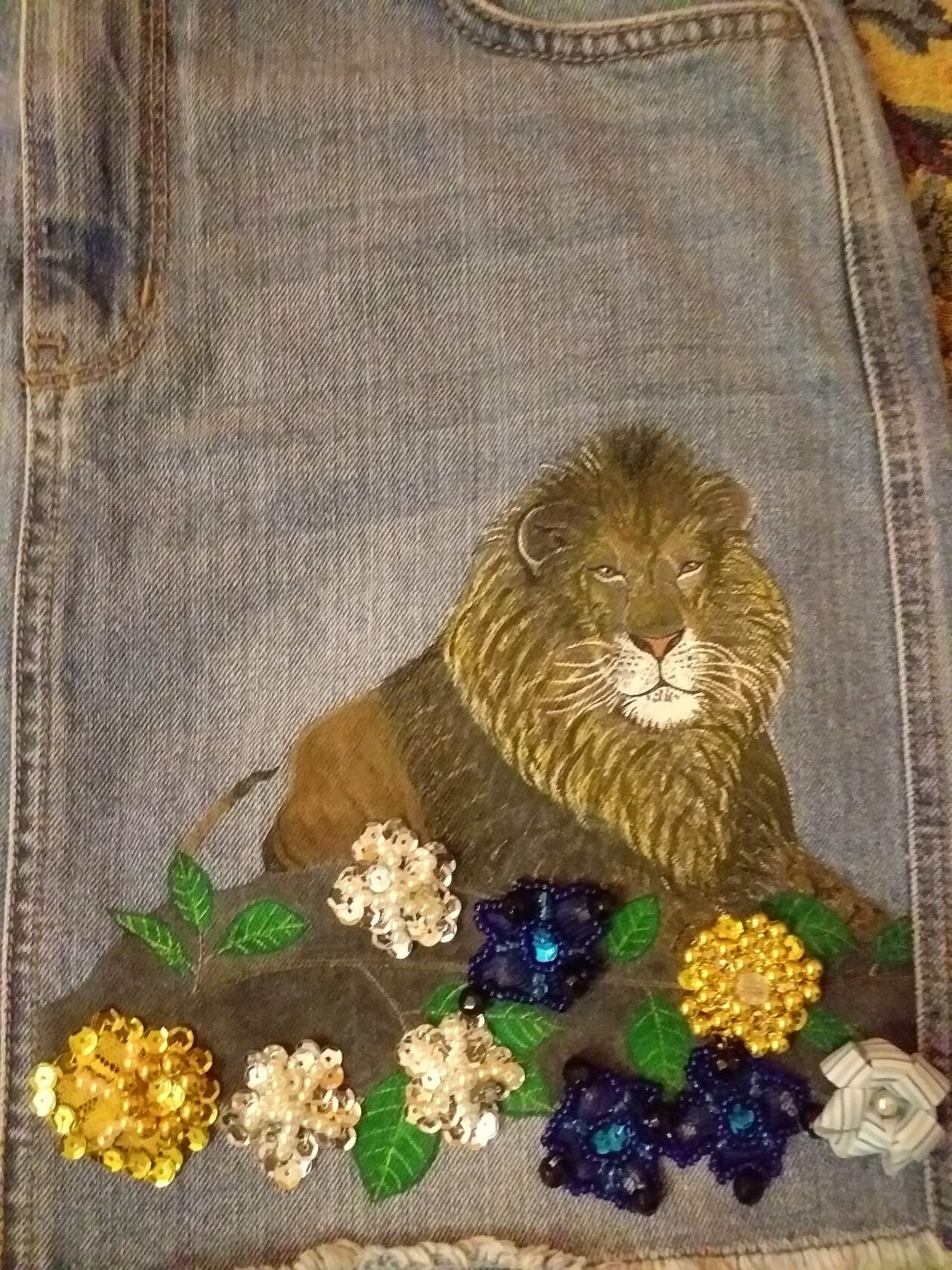 Denimowa spódnica z ręcznie malowanym lwem i aplikacjami z cekinowych kwiatów w odcieniach złota, bieli i granatu.