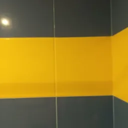 Fragment ściany w łazience wyłożonej niebiesko-żółtymi płytkami ceramicznymi, widoczny narożnik i fragment wieszaka na ręcznik.