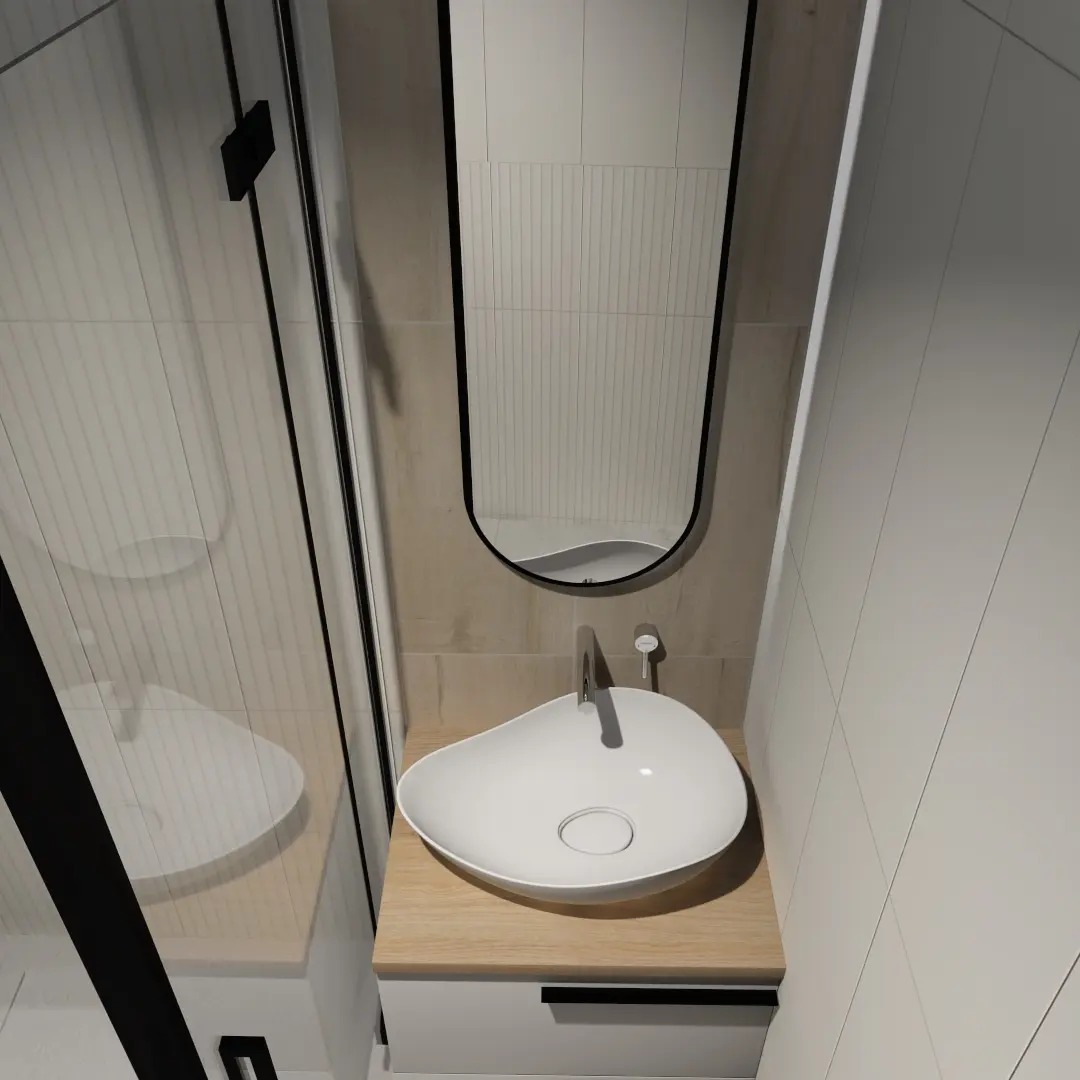 Nowoczesna łazienka w Rybiu: Umywalka w kształcie łzy na drewnianym blacie, minimalistyczny kran i owalne lustro w czarnej ramie, odbijające fragment kabiny prysznicowej z czarnymi profilami.