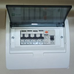 PAWEŁ OPALIŃSKI OPAL ELEKTRO MONTAŻ I POMIARY INSTALACJI ELEKTRYCZNYCH - Otwarta skrzynka elektryczna z bezpiecznikami marki Schaltinger, zamontowana na ścianie o jasnej strukturze.