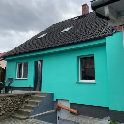 Simplex - Turkusowy dom jednorodzinny z ciemną dachówką i oknami, widok z zewnątrz na elewację i schody wejściowe.