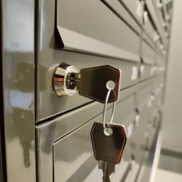 LOCKSTAR Pogotowie zamkowe Artur Gwiazda - Szereg metalowych skrzynek pocztowych z kluczem w zamku jednej z nich, widoczny numer 25818 na kluczu.