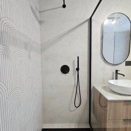 Home Finish Usługi remontowo-budowlane Maciej Twarowski - Nowoczesna łazienka z kabiną typu walk-in, białą umywalką nablatową i czarną armaturą. Na ścianie płytki z subtelnym wzorem w łuki.