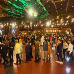 DJ Pawlos Łukasz Pawlos - Sala balowa w rustykalnym stylu z ceglanymi ścianami, oświetleniem punktowym i zielonymi dekoracjami sufitowymi, wypełniona tańczącymi gośćmi w eleganckich strojach.