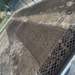 GREEN GARDEN Radosław Wiśnicki - Walec ogrodowy ugniatający świeżo rozłożoną ziemię na przygotowanym terenie pod trawnik, widok z perspektywy operatora maszyny.