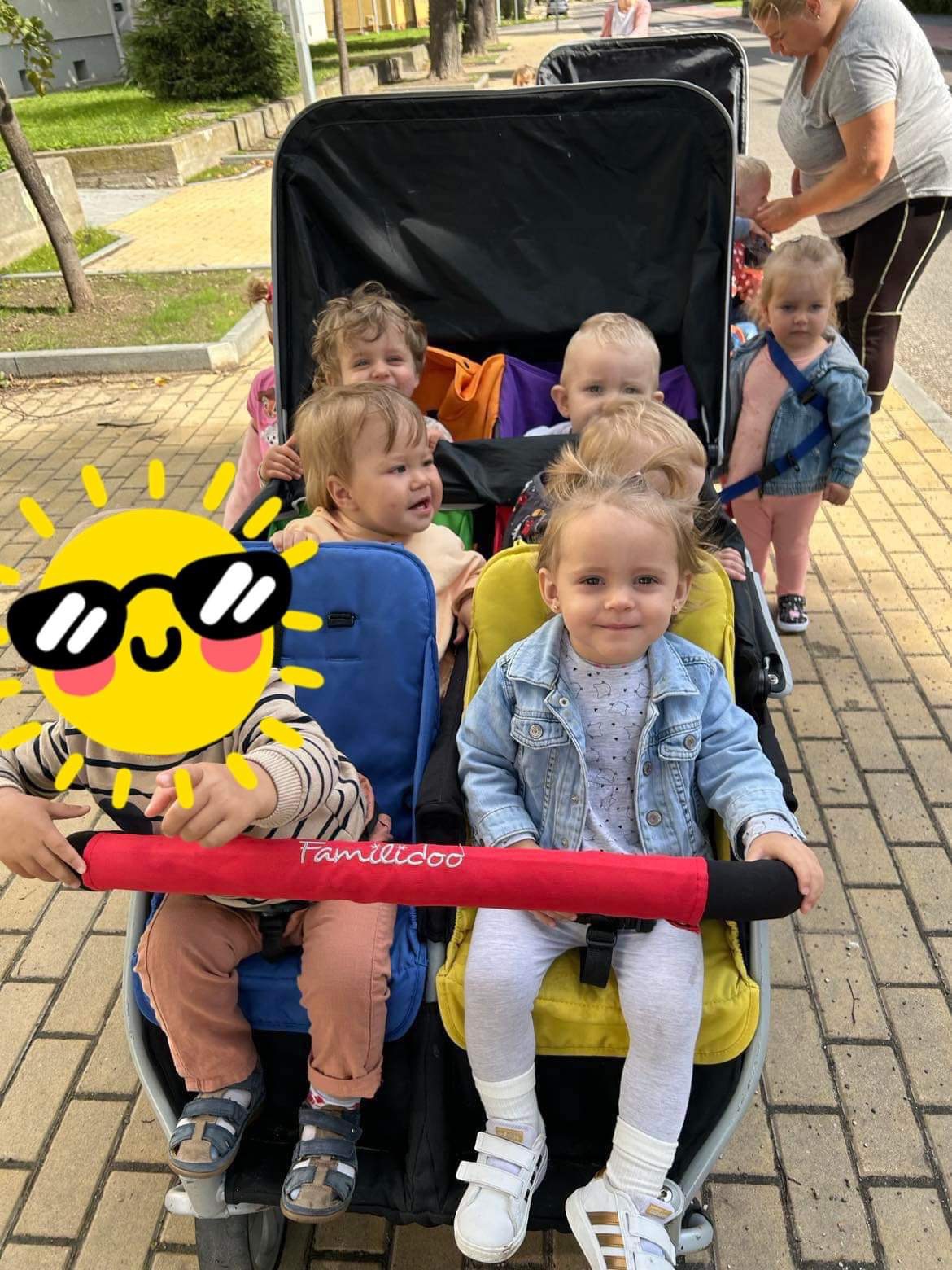 Dzieci w wózku wieloosobowym marki Familidoo w Malborku, pod czujnym okiem opiekunki.