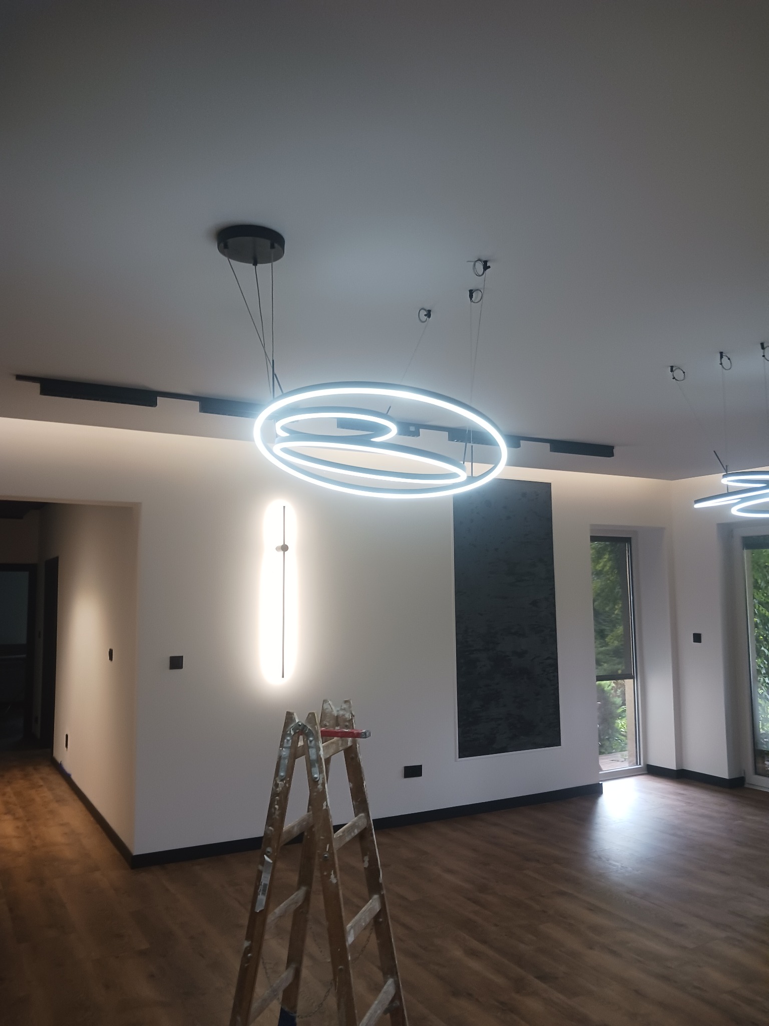 Wnętrze z zamontowanym nowoczesnym oświetleniem sufitowym we Włocławku, widoczna drabina malarska sugerująca trwający montaż.