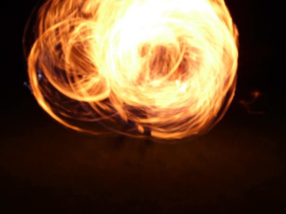 Rozmyte ujęcie kuli ognia na ciemnym tle, prawdopodobnie podczas pokazu fire show.