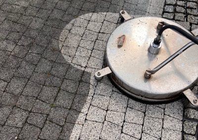 Okrągła szczotka czyszcząca pod ciśnieniem na kostce brukowej, widoczny efekt czyszczenia - różnica w kolorze kostki.